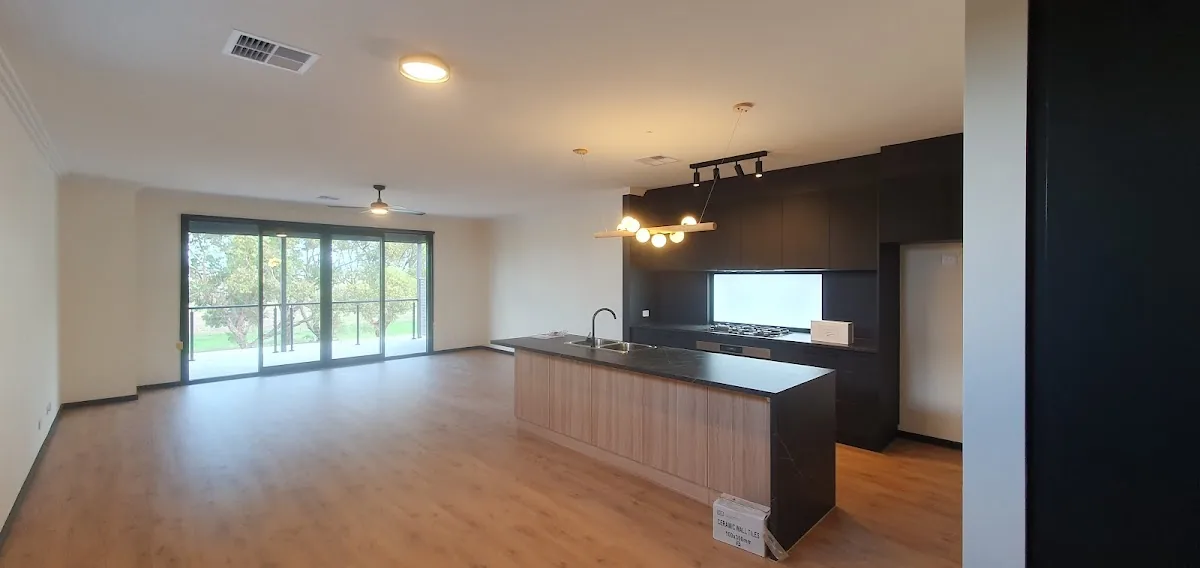 Open plan kitchen with dark cabinetry and pendant lights